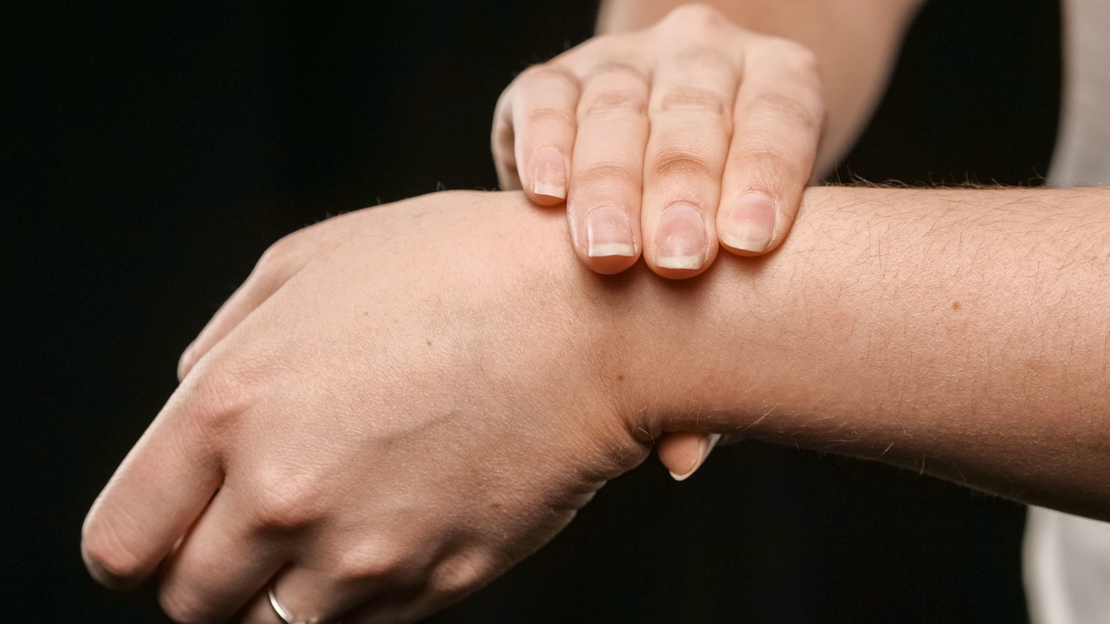 A close view of a hand pressing gently on a wrist, evoking the felt, tactile sensation a wrist wearable delivers.